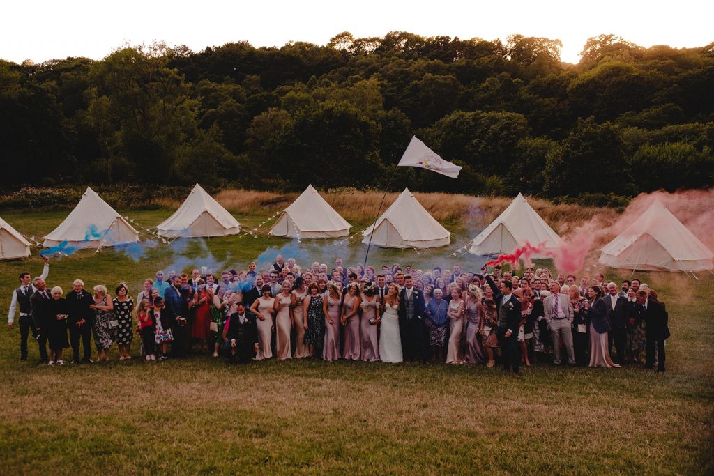 Large group photo of people with smoke bombs while glamping.