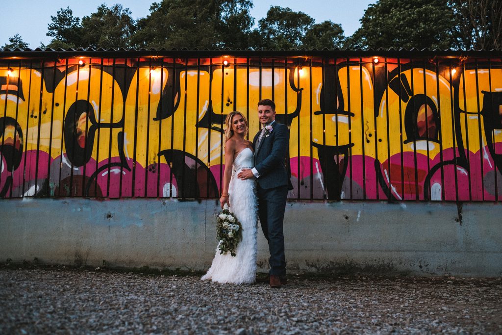 A couple posing in front of a graffiti wall.