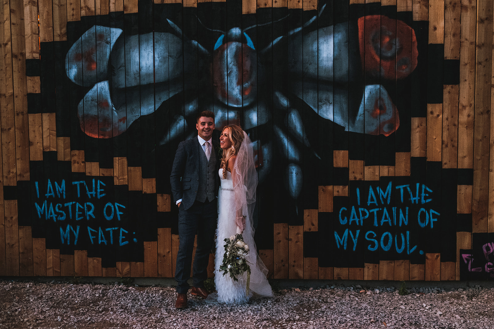 Bride and groom posing in front of graffiti wall.